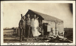 Photograph of Two Men and a Woman in Front of Building